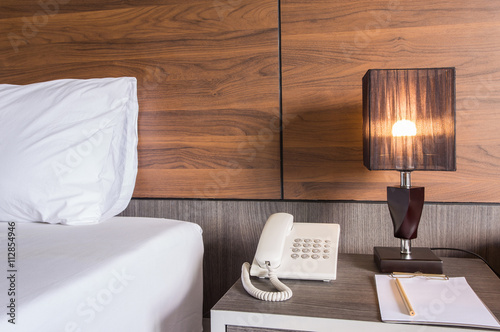 The lamp on the table next to the bed, and telephone.