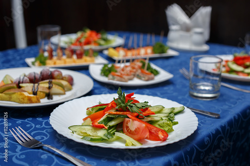Variety of delicious dishes on plates on blue tablecloth at restaurant, selective focus, horizontal view