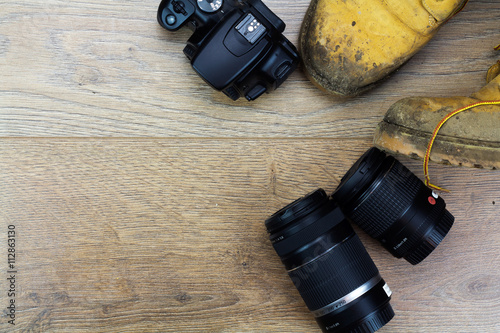 Muddy work boots and cameraequipment on a wooden floor photo