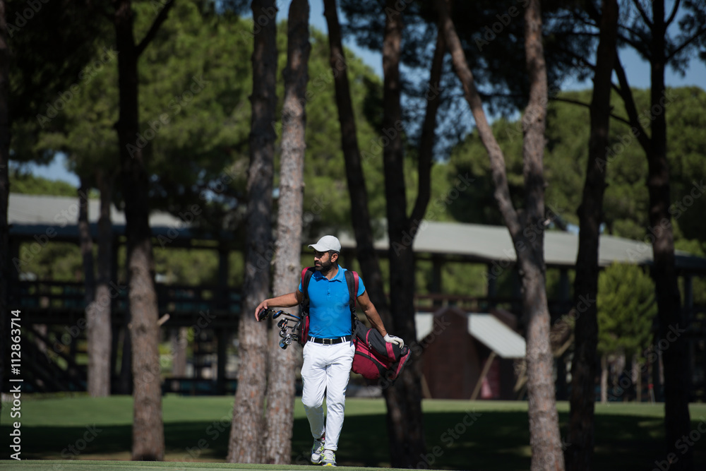Obraz premium golf player walking and carrying bag