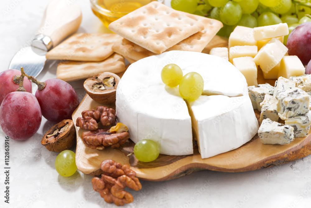 camembert, grapes and crackers on a white table, closeup