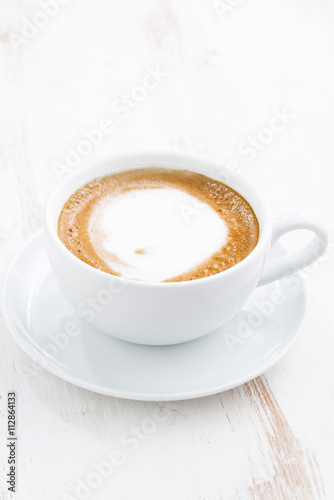 cup of cappuccino on a white wooden table  vertical