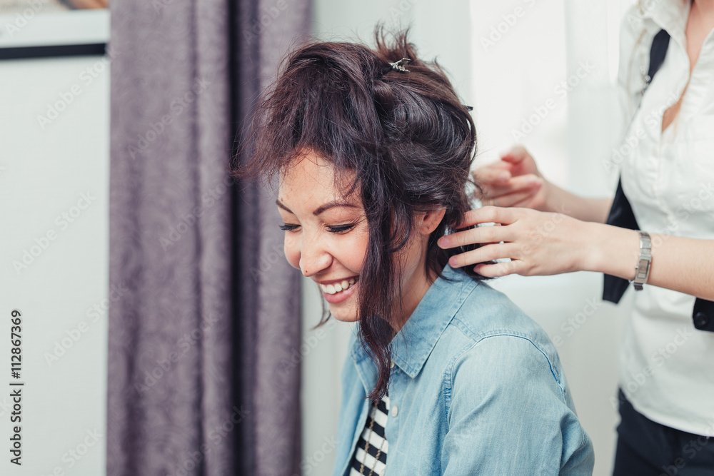 Fototapeta premium A model gets her hair cut and styled by a hipster hair stylist