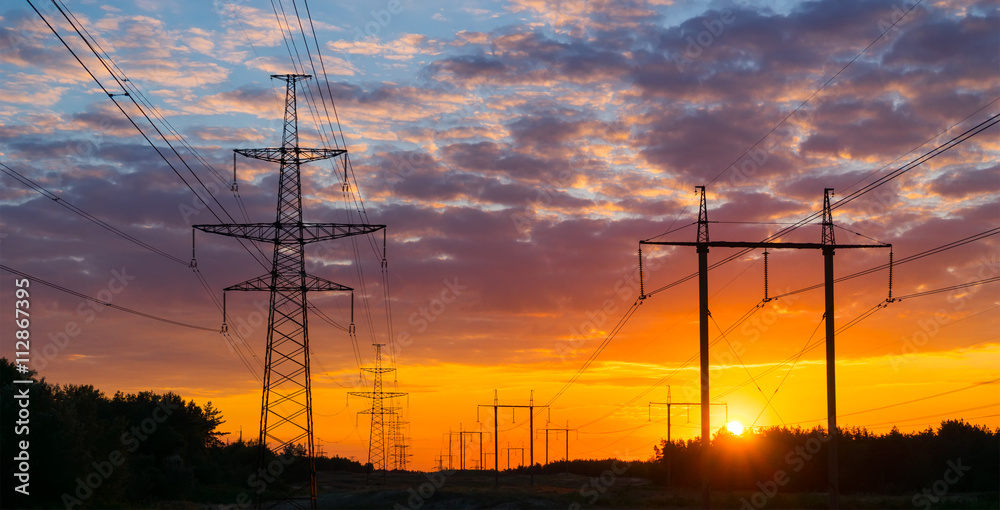 Silhouettes high voltage electric pylon in sunset background