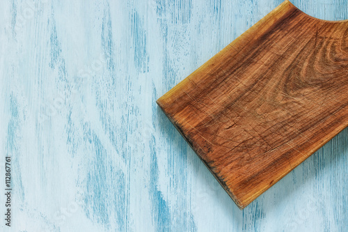 Old wooden cropped cutting board on blue background. Close up. Top view. Flat lay