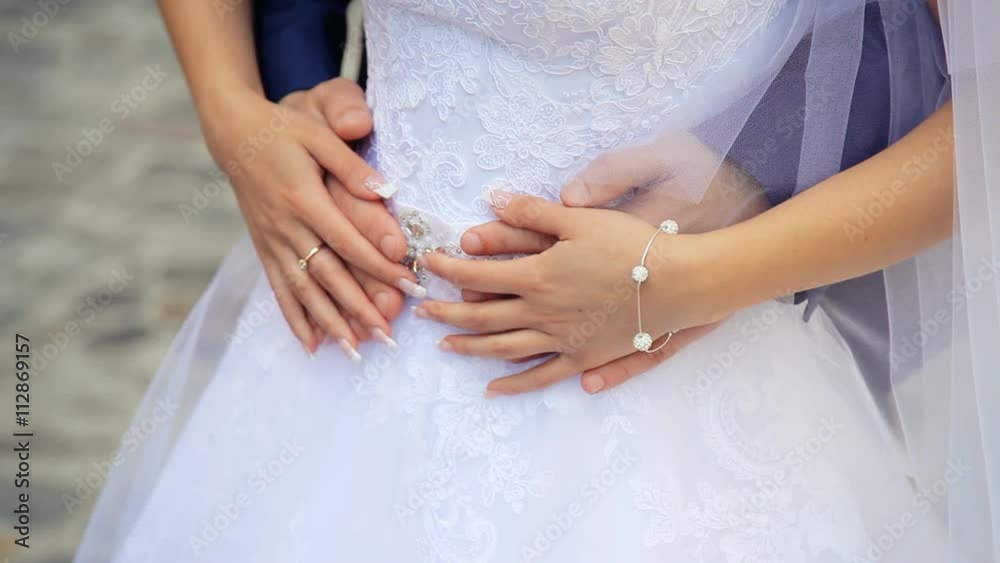 Close-up of young bride and groom in embrace, hands of newlyweds on her stomach Close-up of young bride and groom in embrace, hands of newlyweds on her stomach