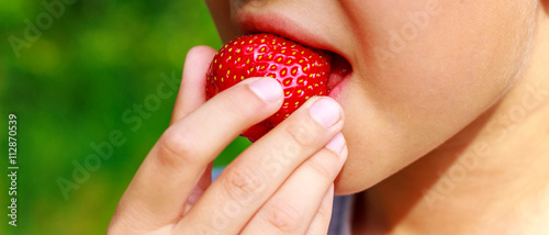 Girl, bites eating, ripe strawberries close-up view.