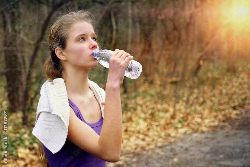 Sport girl runner is jogging on park stop and drink of bottle water path in park. Sport jogging . Sport girl runner is jogging on park stop and drink of bottle water path in park. Sport jogging .