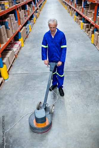  Man cleaning warehouse floor with machine photo