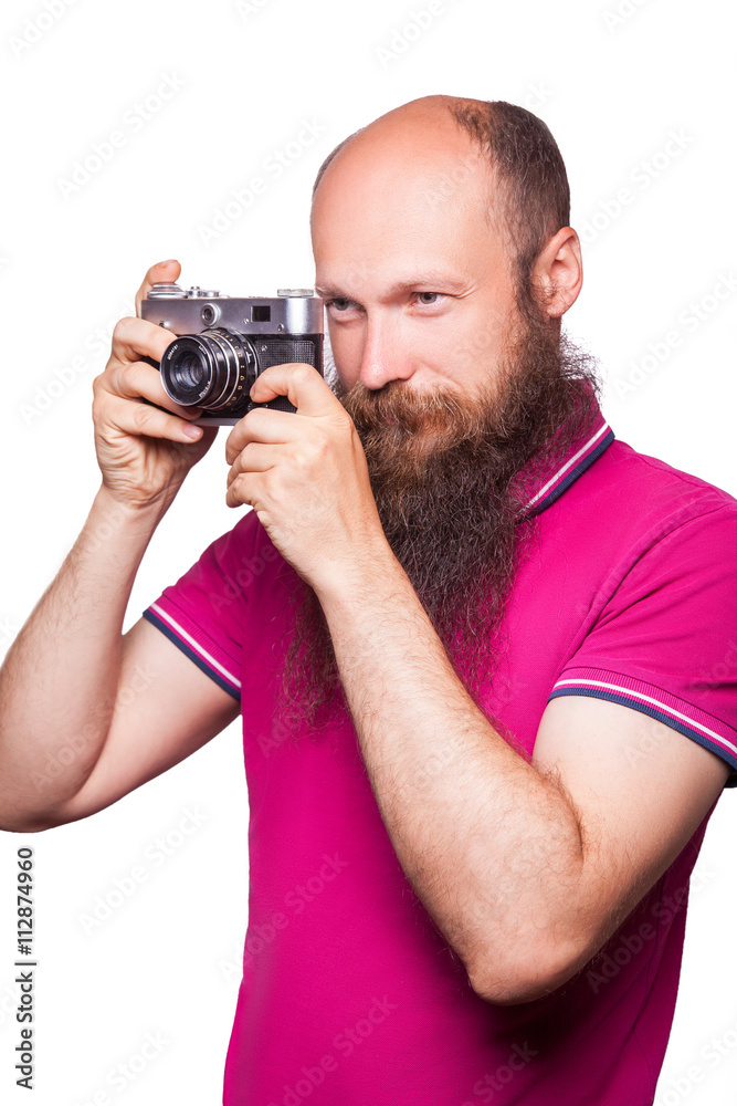 The portrait of bald bearded man photographer with pink t shirt holding classic camera. isolated on white background. studio shot. The portrait of bald bearded man photographer with pink t shirt holding classic camera. isolated on white background. studio shot.