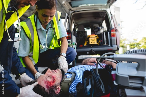 Emergency medical technicians healing injured man on road photo