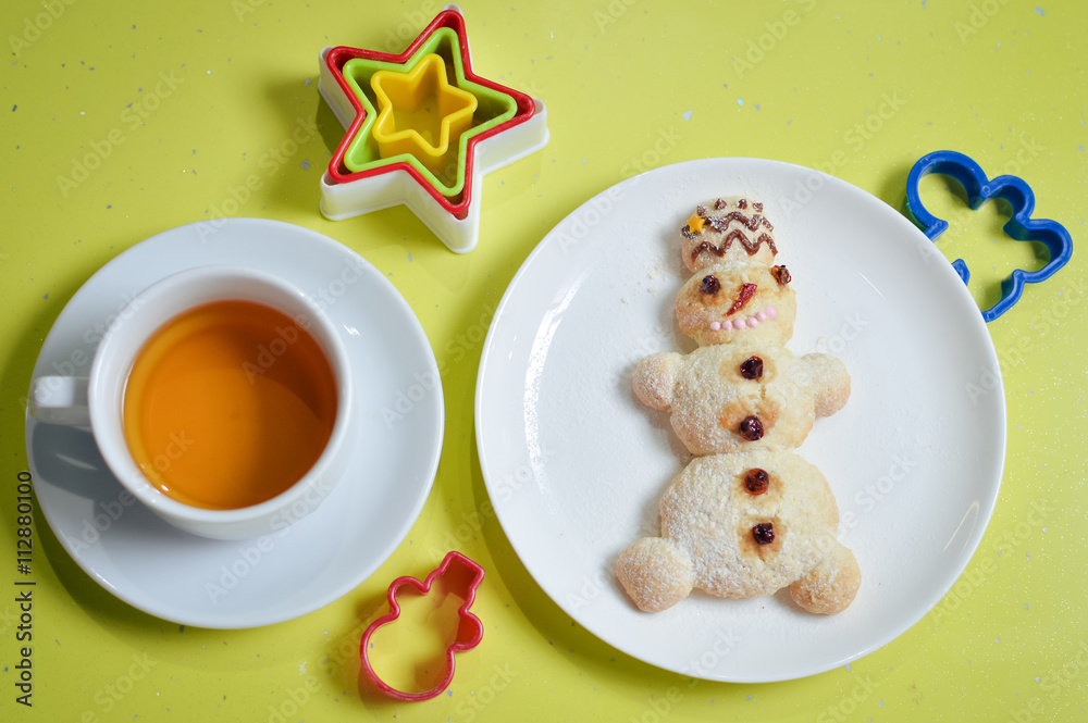 image of snowman on white plate with colorful molds tea isolated on green background image of snowman on white plate with colorful molds tea isolated on green background
