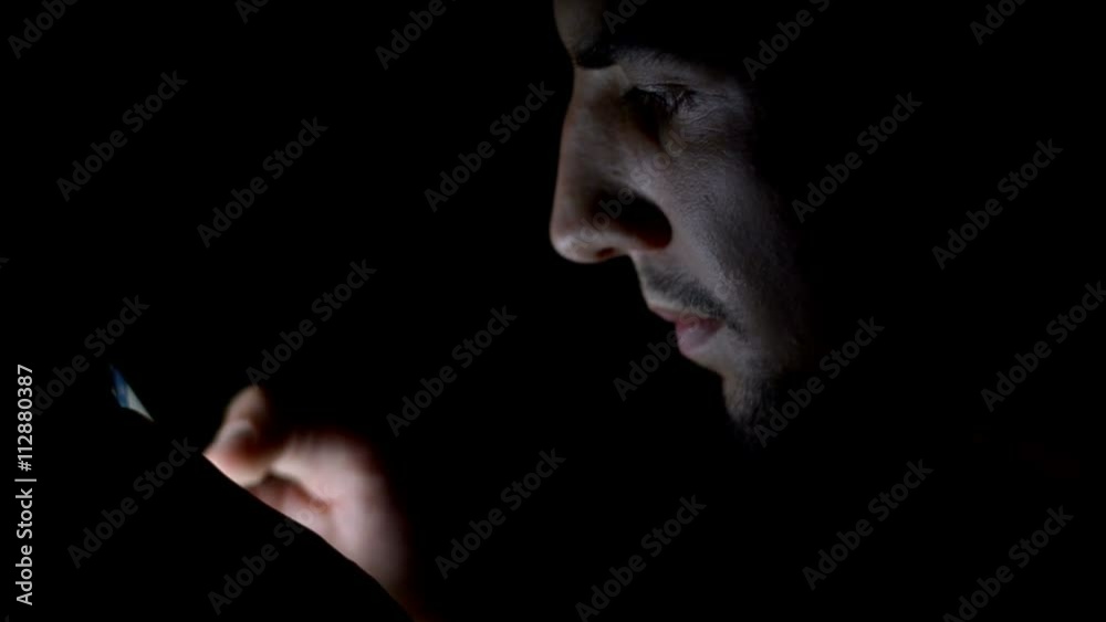 Young man lying on the bed using smartphone at night Young man lying on the bed using smartphone at night