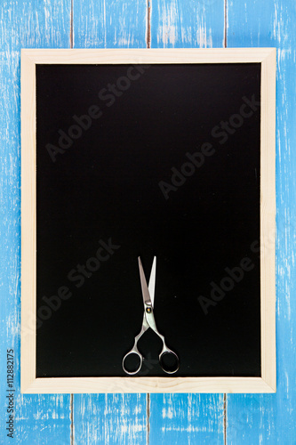 Blank blackboard and scissors hairdresser on wooden table.Templa