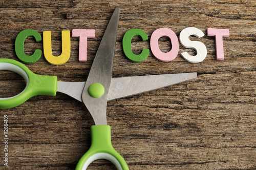 Scissors With CUT COST Word on Wooden Background