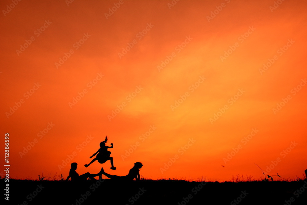 Silhouette of kids playing together at sunset