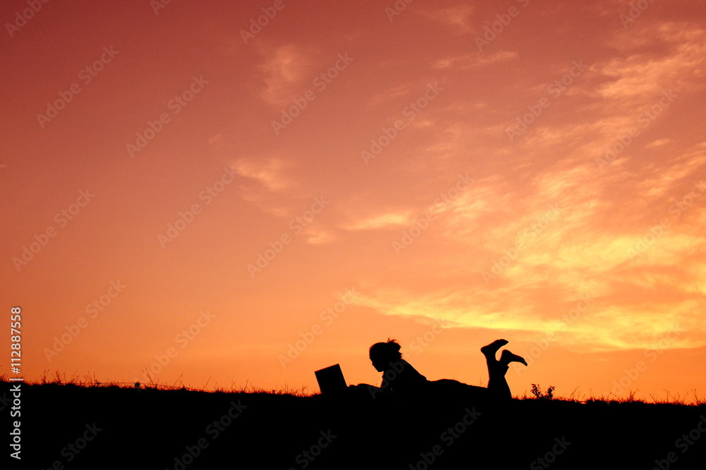 Silhouette women using computer at sunset Silhouette women using computer at sunset