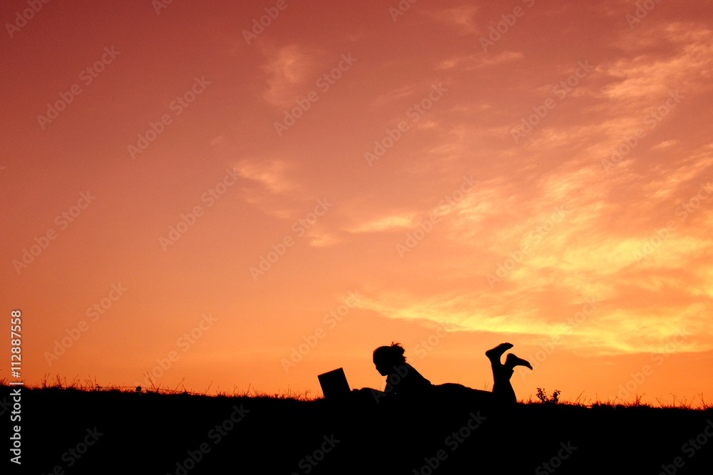 Silhouette women using computer at sunset