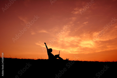 Silhouette women using computer at sunset
