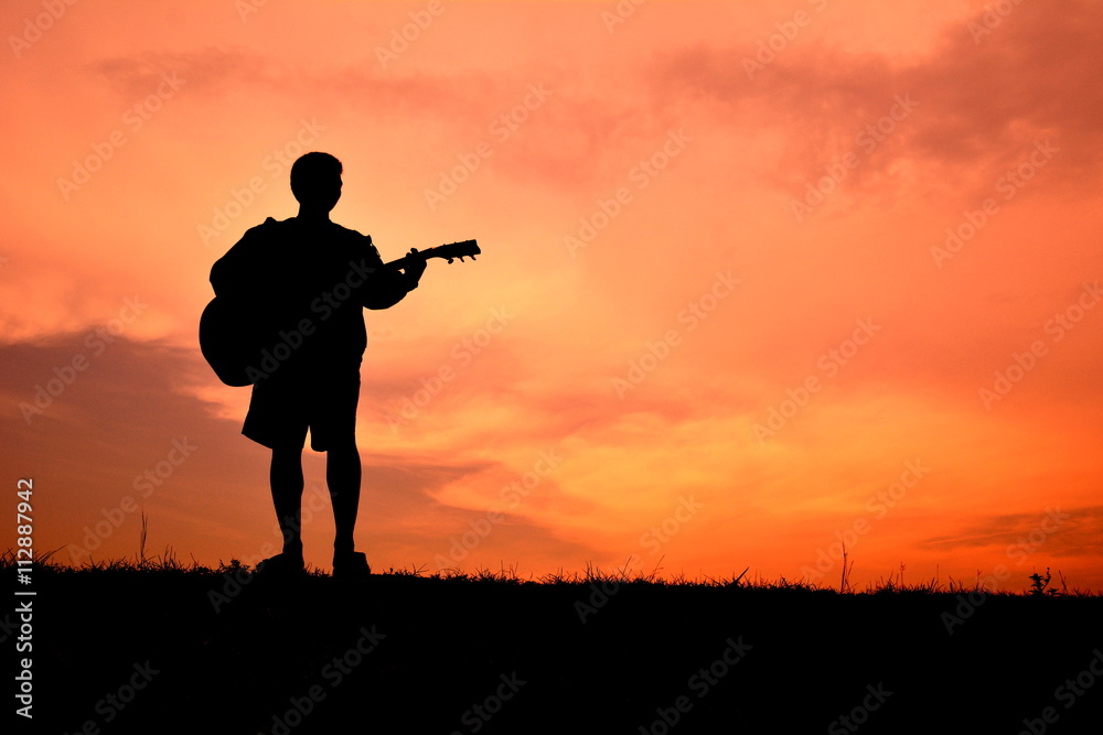 Silhouette man playin guitar in the sunset