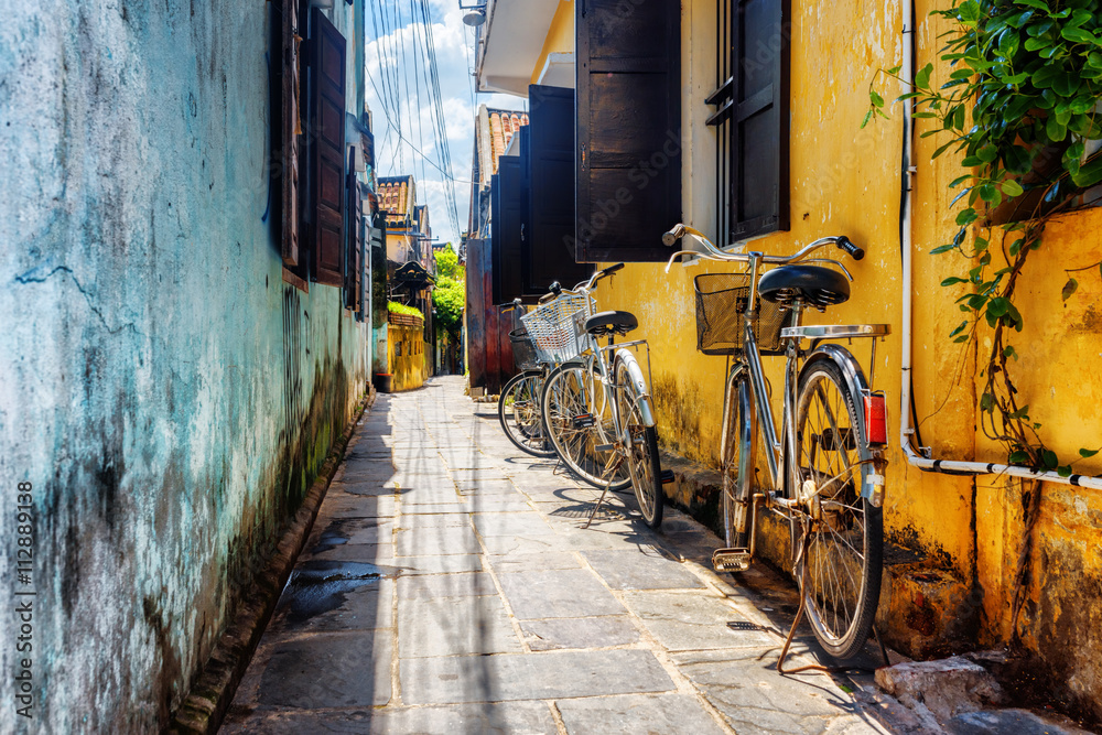 Fototapeta Bicycles parked near yellow wall, Hoi An Ancient Town