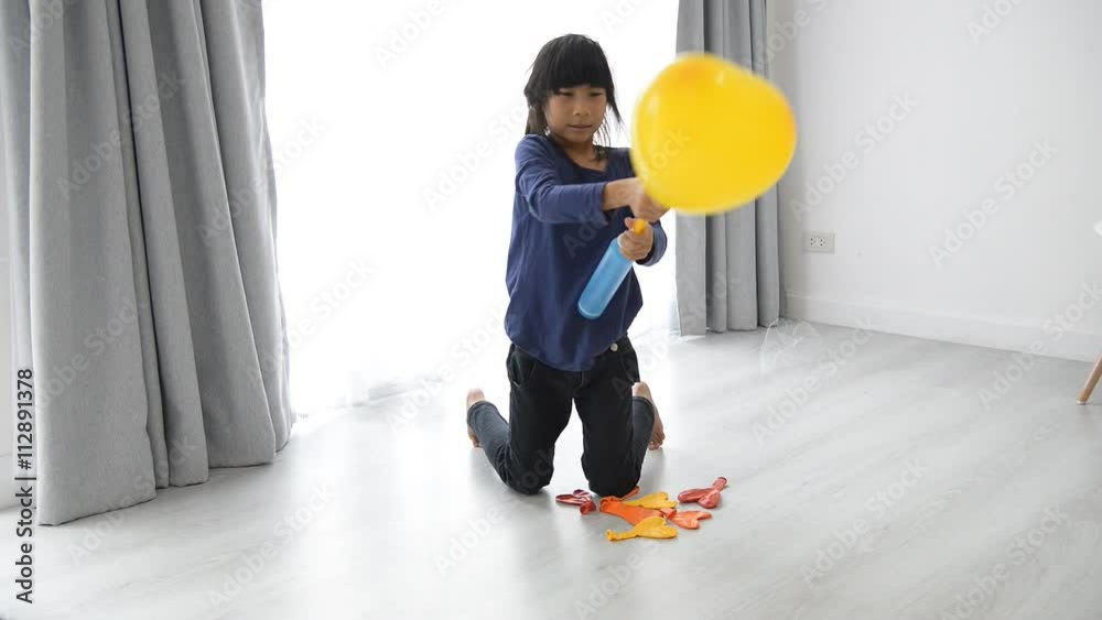 Slow motion girl blowing up a balloon with a hand pump at home.