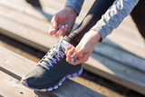close up of sporty woman tying shoelaces outdoors