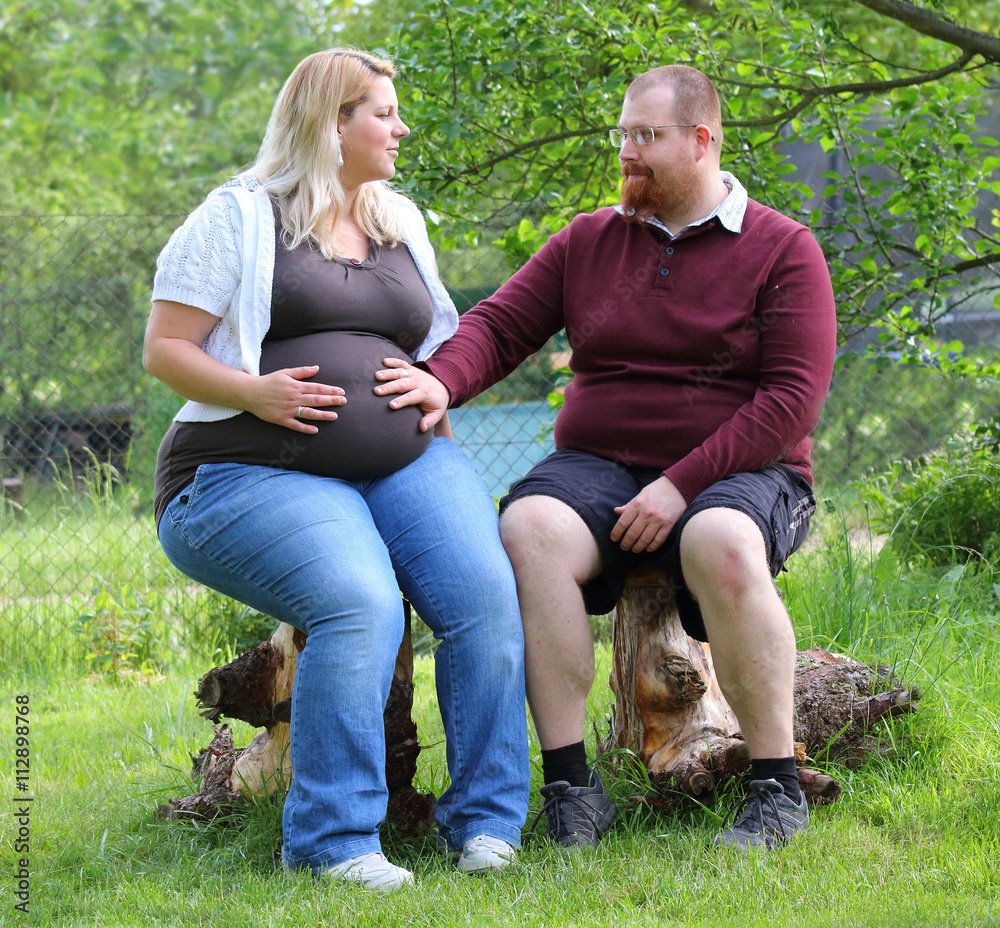 Obese farmer's couple together on garden. Pregnant mother and