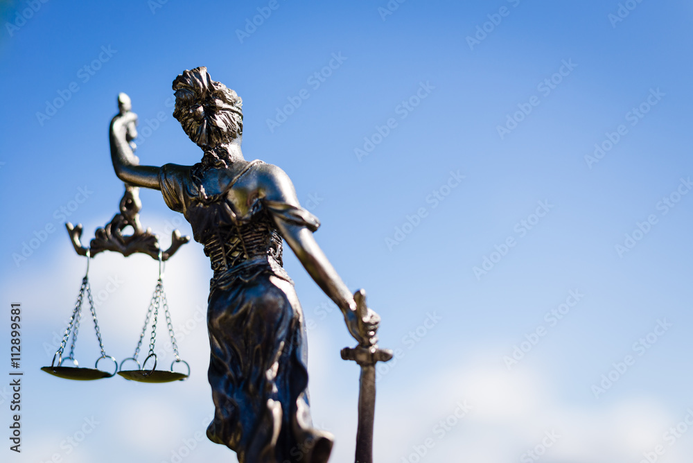 back of sculpture of themis, femida or justice goddess on bright blue sky copyspace background