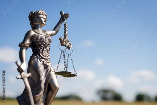 sculpture of themis, femida or justice goddess on bright blue sky copy space background