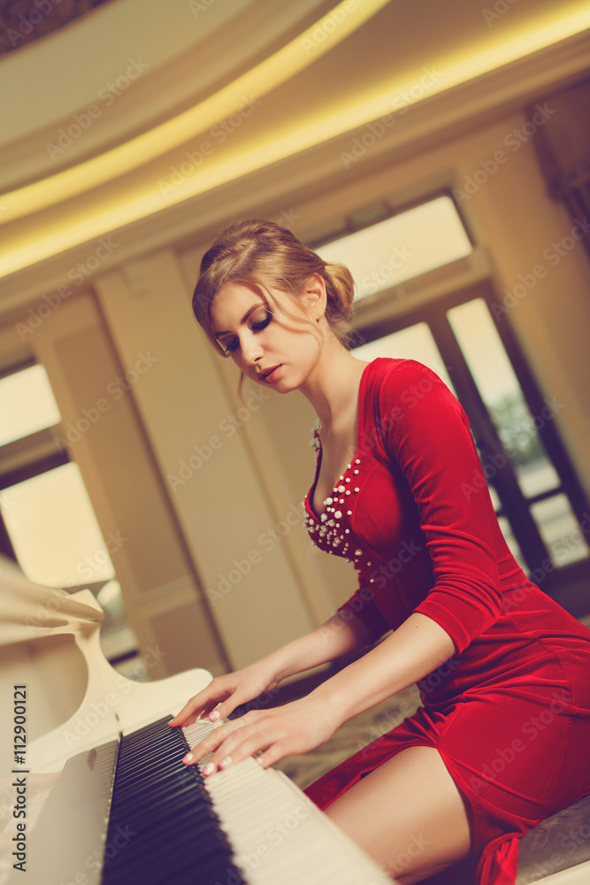 Elegant young woman in evening dress posing in luxury interior with piano. Fashion shot Elegant young woman in evening dress posing in luxury interior with piano. Fashion shot