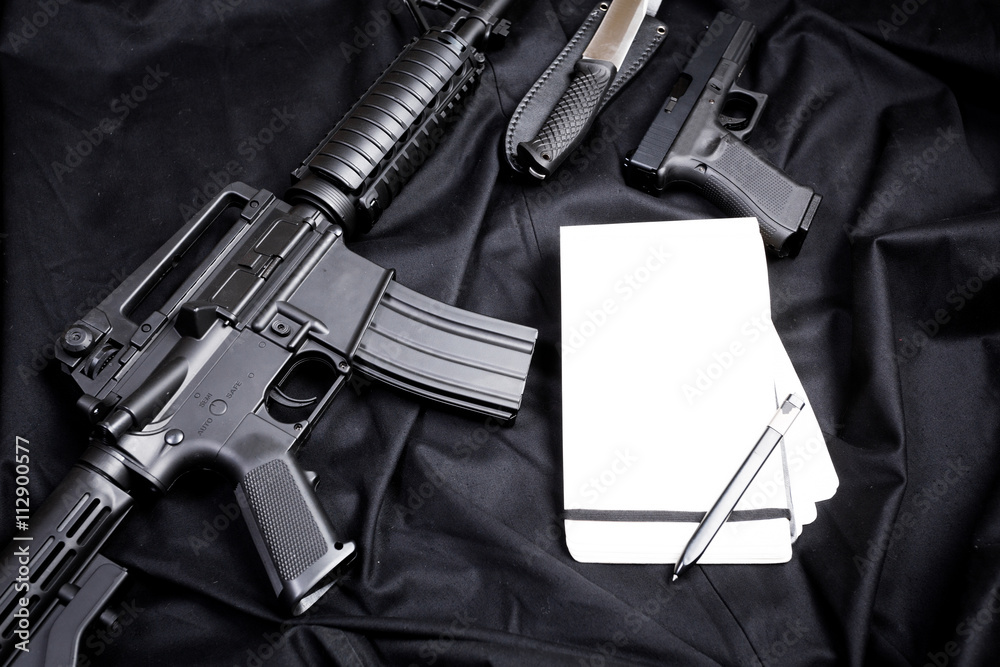Rifle, gun, knife with sheath, compass and notebook with pen on on black cloth Rifle, gun, knife with sheath, compass and notebook with pen on on black cloth