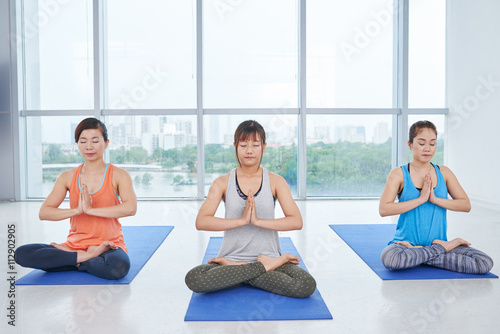 Asian women sitting on mats in yoga position