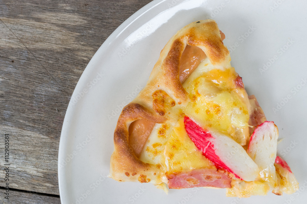 Close up of Pizza Ham and Crab Sticks on white dish and wood background Close up of Pizza Ham and Crab Sticks on white dish and wood background