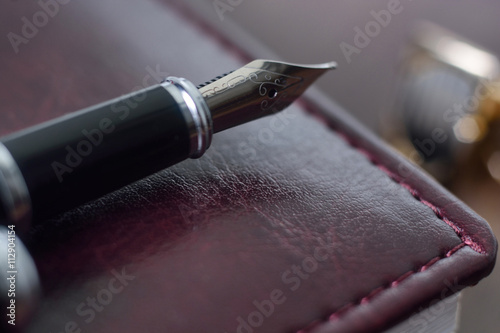 Business accessories on desktop: notebook, diary, fountain pen, cufflinks. Macro with blur and soft focus