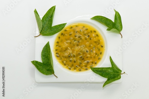 Passion fruit juice wht green leaves on white plate photo