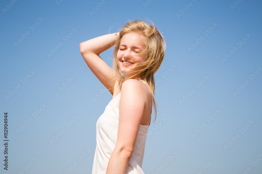 Sweet blonde young girl resting on a beach in a sunny morning