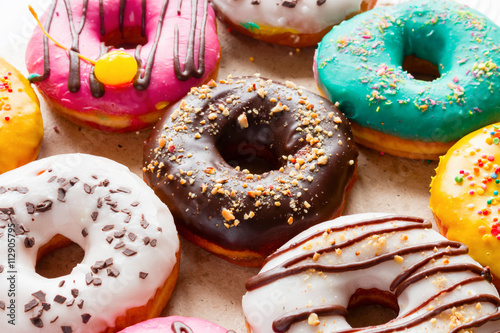 delicious donuts of different flavors on paper close up