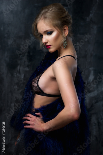 Close-up portrait of gorgeous blonde young woman in celebrity style with perfect make up and hair style wearing sexy lingerie and blue fur. Fashion beauty photo, dramatic look