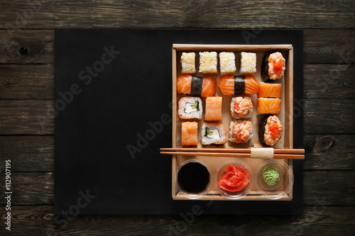 Set of sushi maki and rolls at box on wood.