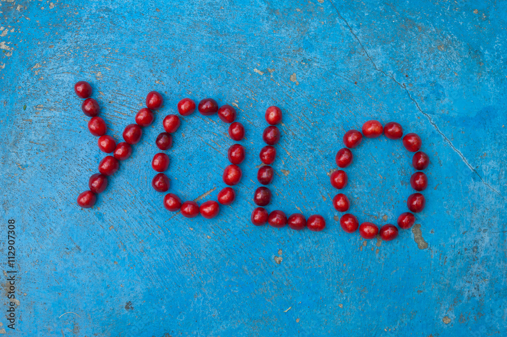 Cherries arranged to form the word YOLO on blue background Cherries arranged to form the word YOLO on blue background