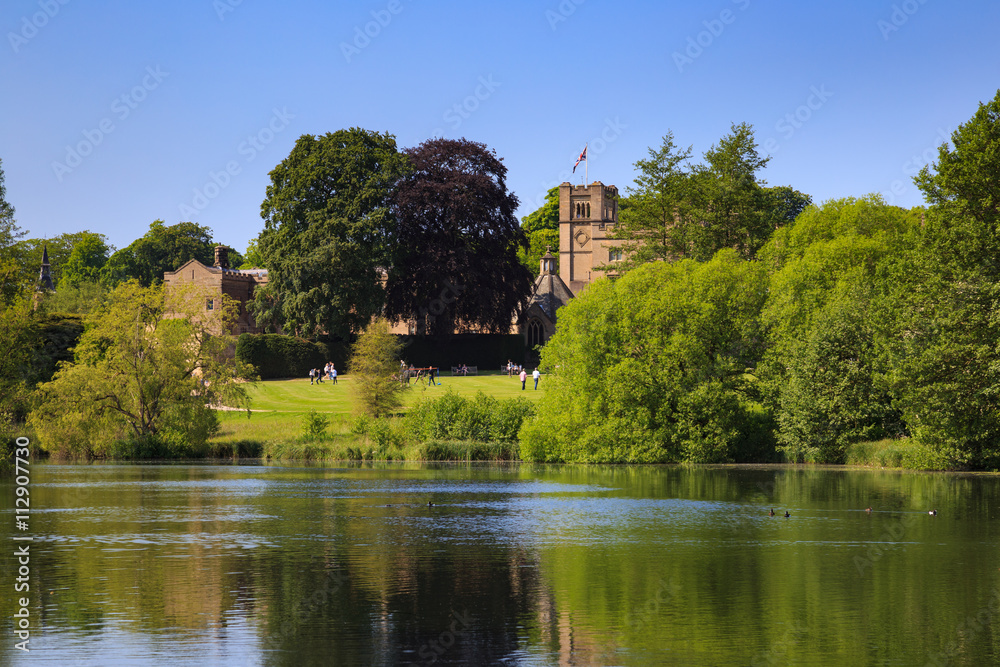 Fototapeta premium NEWSTEAD ABBEY, JUNE 5: View of Newstead Abbey over the Garden Lake, visitors on the lawn. At Newstead Abbey, Nottinghamshire, England. On 5th June 2016.