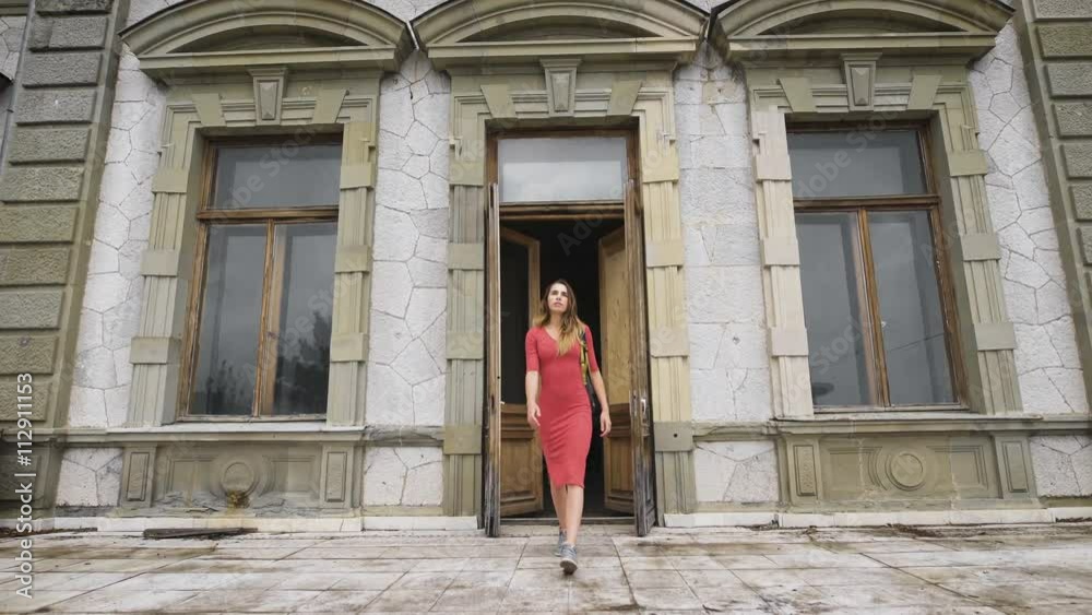 Attractive girl in red dress goes on the balcony of an old manor. Attractive girl in red dress goes on the balcony of an old manor.