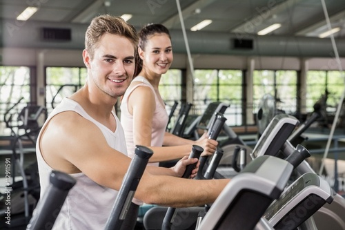 Beautiful woman and man exercising on the elliptical machine