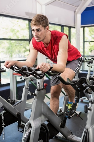 Man working out on exercise bike at spinning class