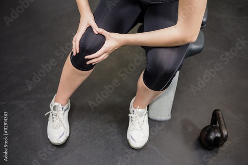 Woman with an injured knee sitting in gym