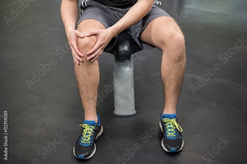 Man with an injured knee sitting in gym