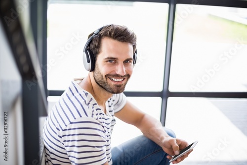 Portrait of man on steps listening to music on mobile phone