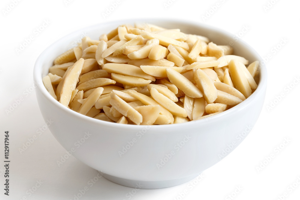 White bowl of peeled slivered almonds isolated on white. White bowl of peeled slivered almonds isolated on white.