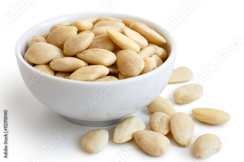 Quadro em tela White bowl of peeled whole almonds on white. Spilled almonds.
